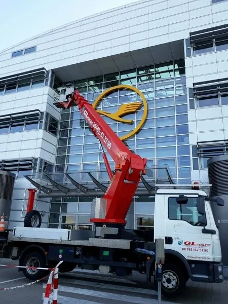 Fassadenreinigung an einem Bürogebäude mit roter Hebebühne